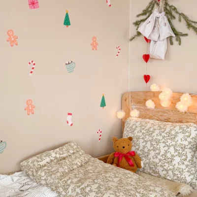 Wall décor with a Christmas motif above a bed, with pine branches and lights hanging overhead.