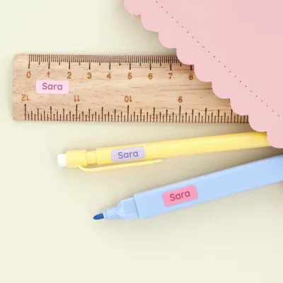 Small mini labels with the name “Sara” placed on a ruler and markers.