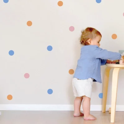 Child playing in a nursery with colorful polka dot wall decals.