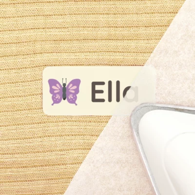 Iron-on name label for kids with butterfly design on fabric surface.