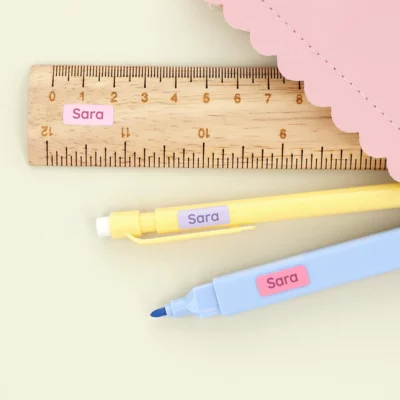 Personalized name labels on stationery items, perfect for organizing school supplies; includes a ruler, pencil, and marker, adorned with custom labels from our collection.