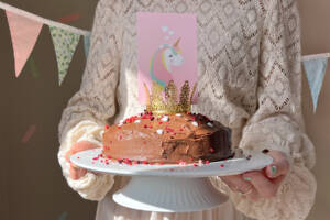 Woman holding a chocolate cake with candles – gluten-free and dairy-free birthday cake.