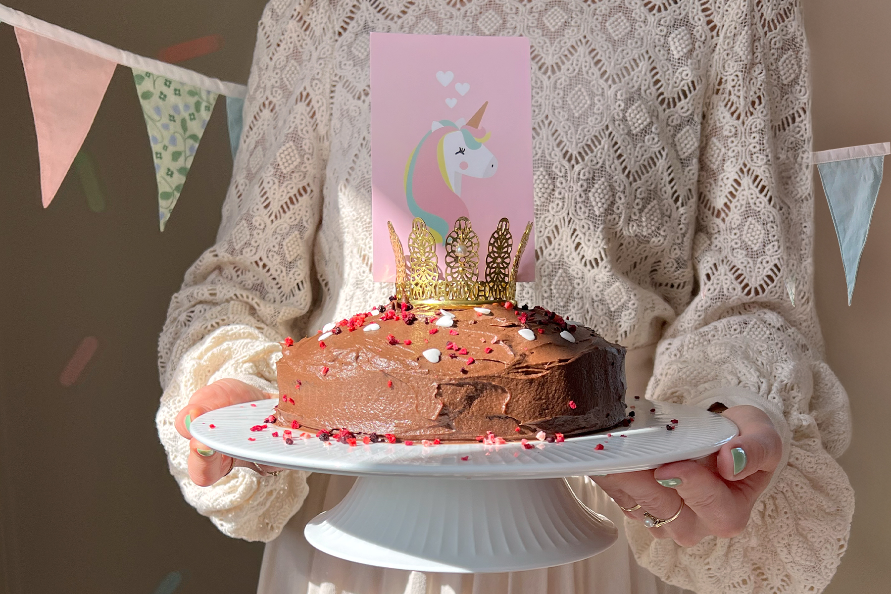 Woman holding a chocolate cake with candles – gluten-free and dairy-free birthday cake.