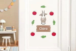 Personalized door sticker for children featuring a cute goat illustration surrounded by red apples and green leaves. Ideal for decorating kids' rooms and adding a playful touch to their space.