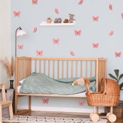 Cozy children's bedroom featuring delicate pink butterfly wall decals, creating a vibrant atmosphere. The room includes a wooden crib with a patterned blanket, adding charm and comfort.
