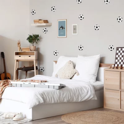 Cozy children's bedroom featuring soccer-themed wall decor, perfect for young sports enthusiasts. The room includes a white bed with fluffy pillows, a stylish wooden nightstand, and framed art prints, creating a playful and inviting atmosphere. Ideal for showcasing personalized name labels and vibrant posters to enhance the space.