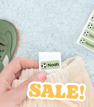 A close-up image showcasing personalized name tags on children's sneakers and clothing, highlighting the name Noah. The scene includes playful colors and a promotional SALE! text.