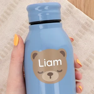 Personalized blue water bottle featuring a cute bear design and the name Liam. Handheld against a textured background, highlighting its child-friendly aesthetic and customizability. Ideal for children's hydration needs or as a unique gift.